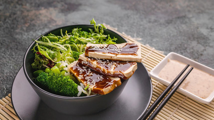 Food banner. Close up Pan-Asian cuisine. Tofu with teriyaki sauce, vegetables in a bowl, nutty spicy sauce. Vegan menu.