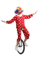 Clown in a red polka dot costume riding a unicycle
