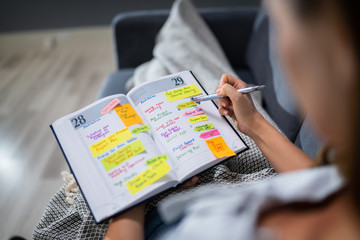 Fototapeta premium Woman Making List Of Office Work In Diary