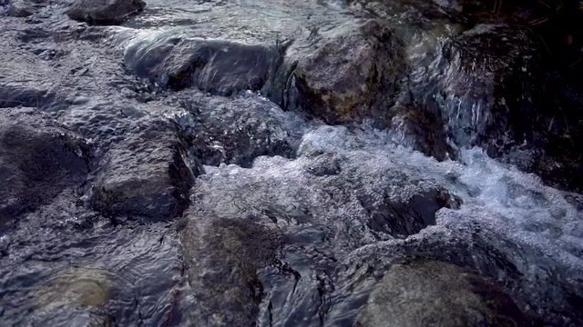Fast flowing clear melting water in creek in mountain river at early spring