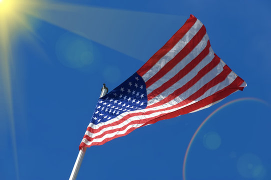 American flag on blue sky with sun rays background. Elements of this image furnished by NASA