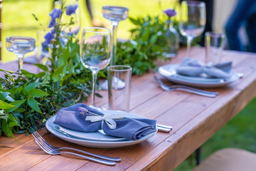 Beautifully decorated wooden table in a summer open-air cafe. Green branch and fresh flowers table decoration