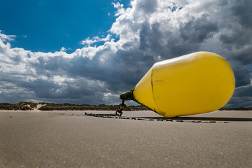  Closeup of a yellow buoy tied at the beach waiting for the next high tide
