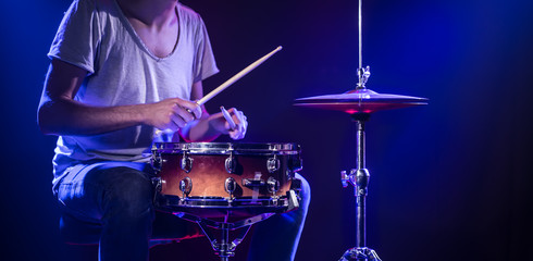 A drummer plays drums on a blue background. Beautiful special effects of light and smoke. The process of playing a musical instrument.
