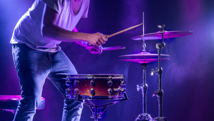 A drummer plays drums on a blue background. Beautiful special effects of light and smoke. The...