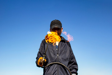 a burner with a fire on a blurred background of a working roofer in dirty clothes