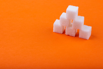Cubes of white sugar on an orange background