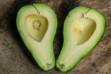 Avocado fruit cut two halves closeup on wooden surface