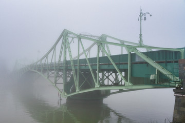 Ancient riveted bridge in heavy fog.