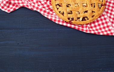 round traditional baked cherry pie on a red textile napkin