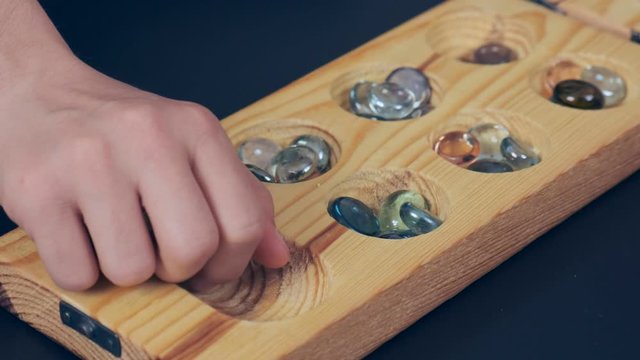 wooden mangala game, mangala game board and glass marbles, on black background