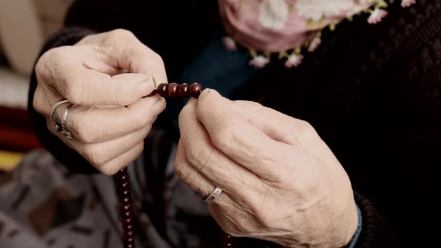 old woman has a rosary in her hand, a woman worshiping,