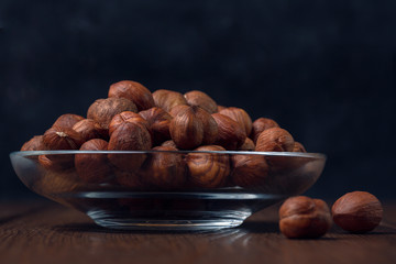 Hazelnuts in a glass plate close-up on a wooden background