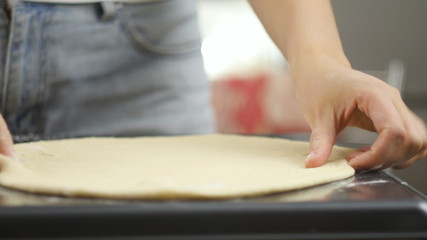 Cooking pizza. The chef prepares the pizza dough. A man or woman is engaged in home business preparing a delicious pizza