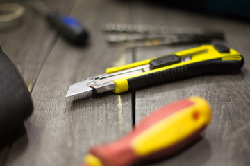 Tools on the table.  On the table is: a knife for paper, a screwdriver ( in no focus ) and a drills...