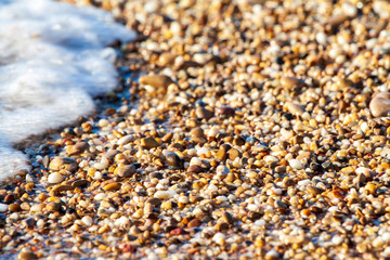 sea pebbles colored granite on the beach background stones. The shore of the beach with sand and pebbles washed by the waves of the sea.