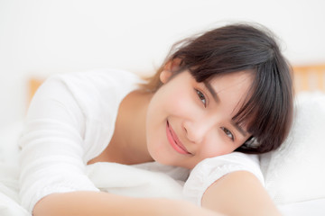 Obraz na płótnie Canvas Beautiful portrait young asian woman lying and smile while wake up with sunrise at morning, girl with happy annd fun in the bedroom, lifestyle and relax concept.