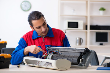 Young repairman repairing air-conditioner at warranty center