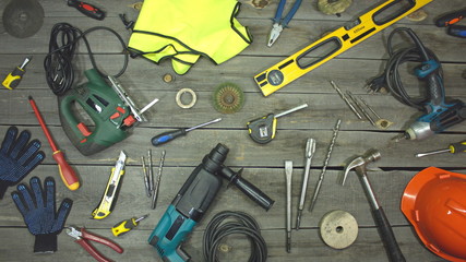 A variety of electro and hand tools and special clothing. Top view.  On the table are tools for various types of construction and repair work on wood, metal, concrete, plastic and other materials.