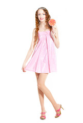 A young sexy woman with curly hair, blue eyes and long legs in a tiara and a pink short dress with a lollipop in her hand, on a white background, isolated.
