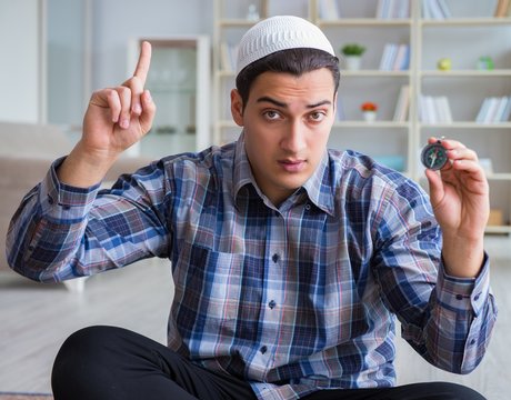 Young muslim man praying at home