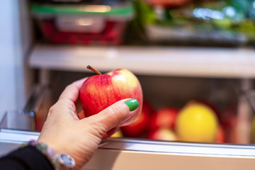 Closeup of woman's hand taking an apple out of the fridge
