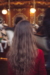 Fototapeta premium Portrait of a beautiful young girl in front of a carousel horse