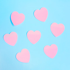Some heart-shaped pink sticky notes on a blue background. Valentine's day, love concept.