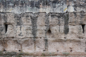 old wall of an ancient castle fom middle ages - surface of stone and clay with cracks, holes, moisture and sandy texture background