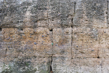 yellowish stone wall of an ancient castle - surface with cracks and sandy texture background
