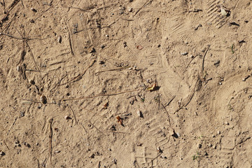 irregular ground of sand and pebbles, and shoe footprints - beach or park floor texture background