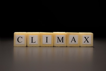 The word CLIMAX written on wooden cubes isolated on a black background...