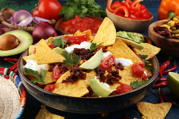 mexican nacho chips garnished with ground beef, guacamole, melted cheese, peppers and cilantro...