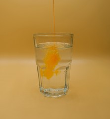 Glass of water with burst of color from water enhancer