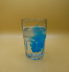 Glass of water with burst of blue color from water enhancer