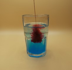 Glass of water with burst of red and blue color from water enhancer