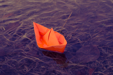 A boat made of colored paper in the snow. Origami handicraft.