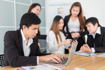 smart asian man officer typing report with laptop, he prepare information to executive conference, leadership and organization management, asian officer team discuss together