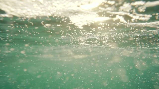Underwater, sea waves with sunrays shining through the water