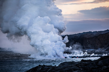 Fototapeta na wymiar Lava pouring into the sea causing steam clouds