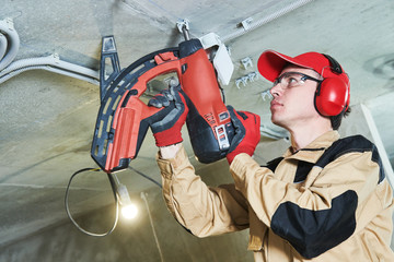 electrician service. Installer nailing tube holder for cable conduit