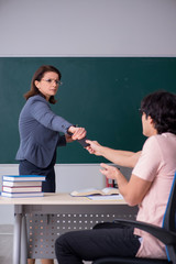 Old female teacher and male student in the classroom