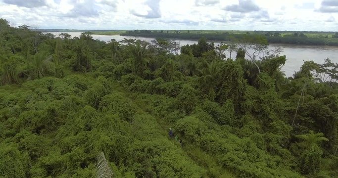 Two Men and Brown Woman with Indigenous Features Walking in the Bolivian Amazon with a Plastic Bucket, Wooden Stick and a Bag