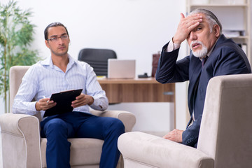 Old man visiting young male doctor psychologist