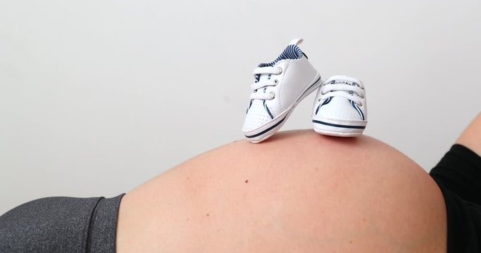 Baby shoes on top of pregant woman belly