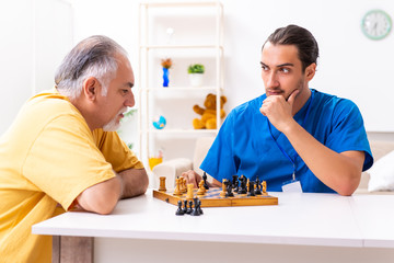 Young male doctor visiting old patient at home