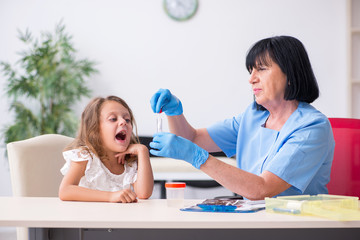 Little girl visiting old female doctor