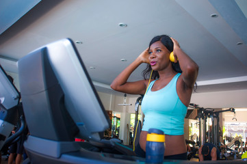 fitness lifestyle  portrait of young attractive and happy black afro American woman training at gym all doing treadmill workout adjusting headphones listening to music