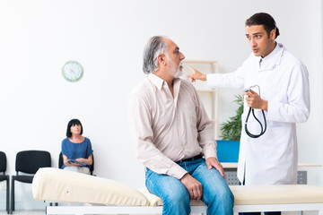 Obraz premium Old couple visiting young male doctor