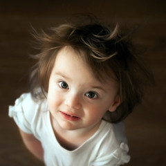 little shaggy girl with big eyes stands and looks up. top view close up